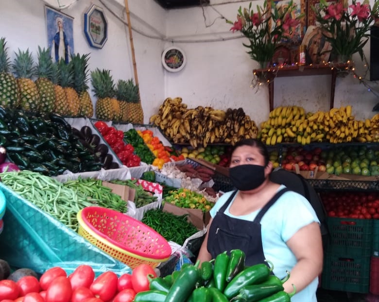Una mujer en un puesto de frutas y verduras.